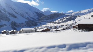 Un pueblo cubierto de nieve con casas de madera tradicionales y una iglesia, rodeado de montañas.