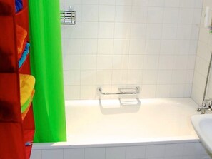 A bathroom with a white bathtub, a shower area, and a towel rack. - Tgésa Bienviver, (Sedrun), 136.02 by Interhome (Sedrun)