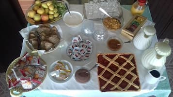 A table with various food items and condiments, including fruits, bread, and packaged snacks.