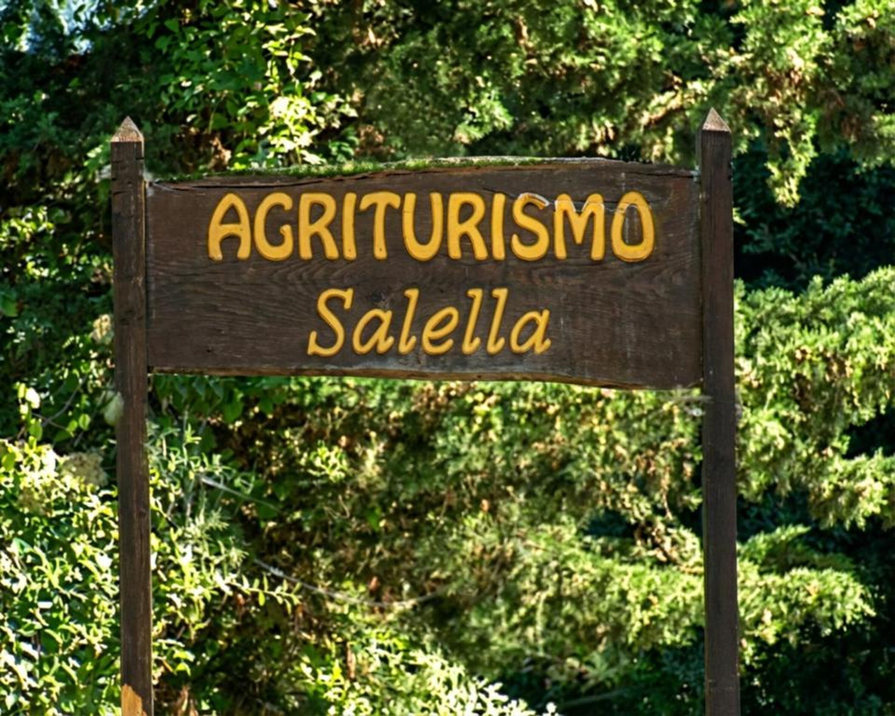 Une enseigne en bois sur laquelle est inscrit « AGRITURISMO Salella ».