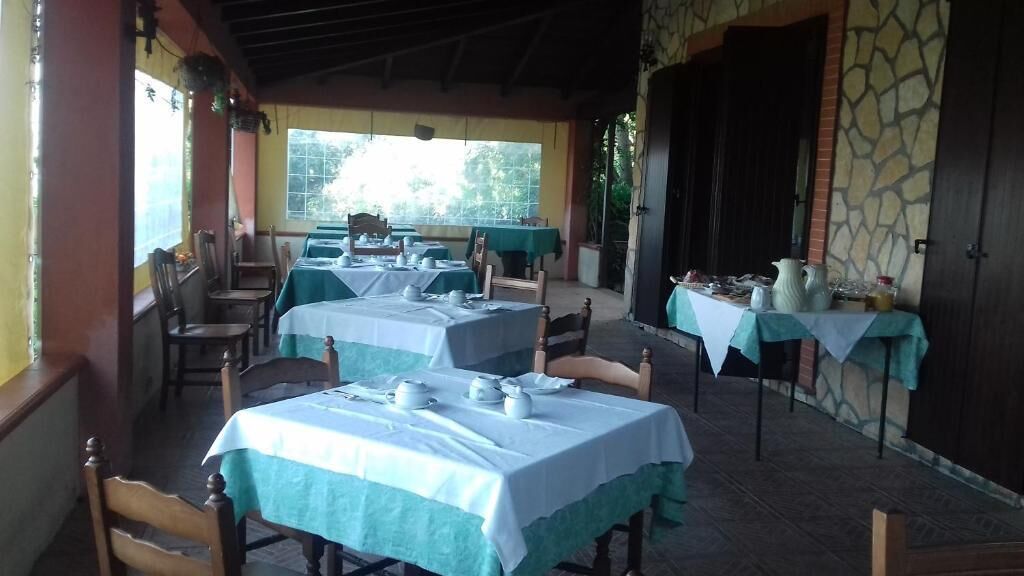 A restaurant with tables set for dining, a stone wall, and a covered outdoor area.