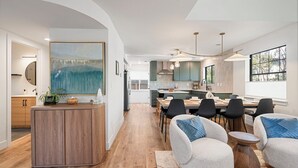Une cuisine moderne avec un coin repas, des meubles en bois et un grand tableau.