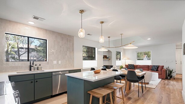 Une cuisine moderne dotée d’un îlot central, de tabourets de bar et de luminaires suspendus.