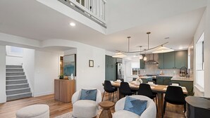 Une cuisine moderne avec un coin repas, un escalier et un salon doté de sièges.