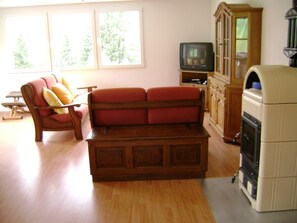 Ein Wohnzimmer mit einem roten Sofa, einem Fernseher, einem Schrank und einem Kamin.
