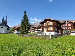 A rural village with traditional wooden houses, a church, and a mountain in the background. - Tgèsa Margeritha Frei M., (Sedrun), 253.01 by Interhome (Sedrun)