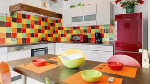 A kitchen with a colorful tile backsplash, white cabinets, and a red refrigerator. - Gîte La Bergerie – With Pool! (Saint-Michel-en-l'Herm)