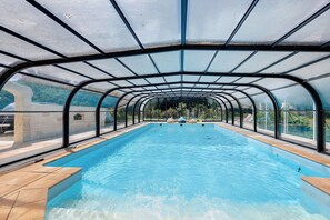 Una piscina interior con techo de cristal, agua cristalina y vistas del paisaje circundante.