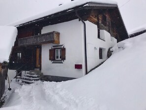 Ein zweistöckiges Gebäude mit einem mit Schnee bedeckten Dach und Treppen zum Eingang.