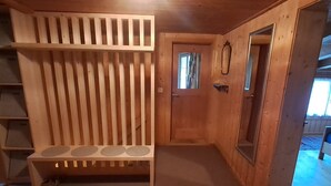 Een houten kamer met een bank, een deur en een spiegel.