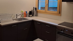 Een moderne keuken met een inbouwvaatwasser, een koffiezetapparaat en een raam met uitzicht op een besneeuwd landschap.