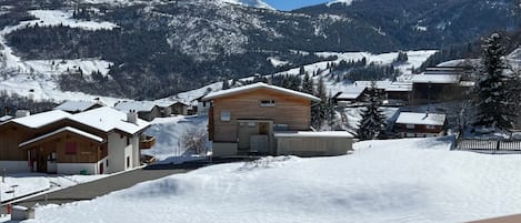 Un village de montagne enneigé, avec des bâtiments en bois et un ciel dégagé.