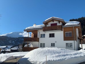 A multi-story chalet with a balcony, surrounded by snow, set against a mountain backdrop. - Casa Diala Panorama, (Segnas/Disentis), 1106 by Interhome (Disentis)