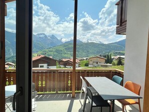 A balcony with a table and chairs, a view of a mountain range, and a wooden fence. - Casa Diala Panorama, (Segnas/Disentis), 1106 by Interhome (Disentis)