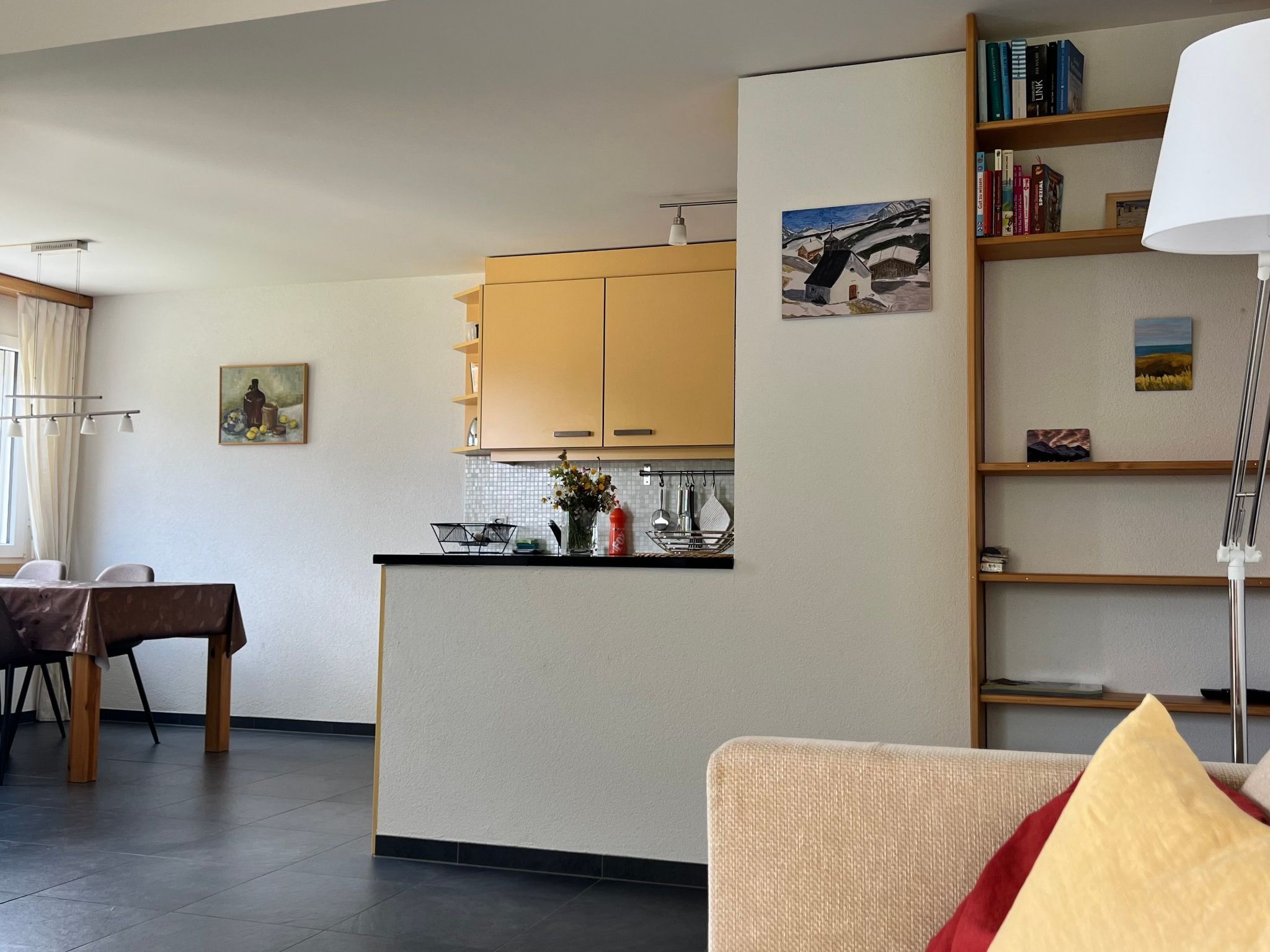 Un espace de vie compact comprenant un coin cuisine, un espace repas et une bibliothèque.