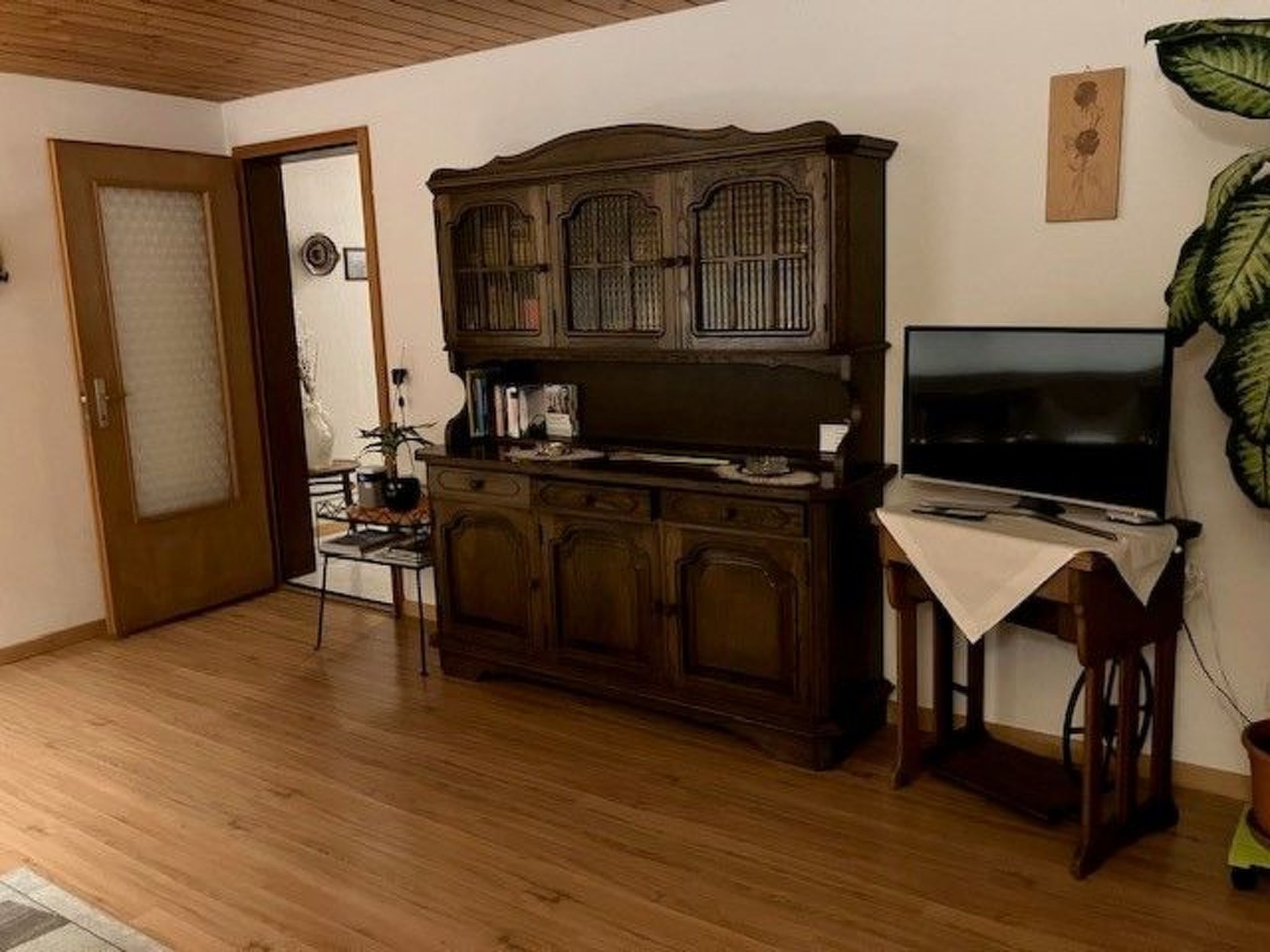 Uma sala de estar com um armário de madeira, uma televisão e uma poltrona.