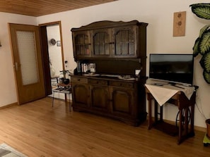 Ein Wohnzimmer mit einem Holzkasten, einem Fernseher und einem Sessel.