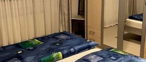 Une chambre avec deux lits, une armoire et un miroir.
