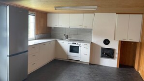 Eine kleine Küche mit weißen Schränken, einem eingebauten Ofen und einem Fenster.