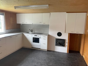 Eine Küche mit weißen Schränken, einem Backofen, einer Spüle und einem Fenster.