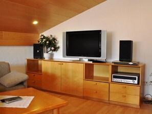 A living room with a television on a wooden cabinet, a plant, and a stereo system. - Disentiserhof Hönig, (Disentis/Mustér), 1048 by Interhome (Disentis)