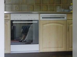 Eine Küche mit Einbauofen, Geschirrspüler und Holzschränken.