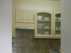 Eine Küche mit Holzausstattung, einer gefliesten Spritzschutzwand und einem eingebauten Backofen.
