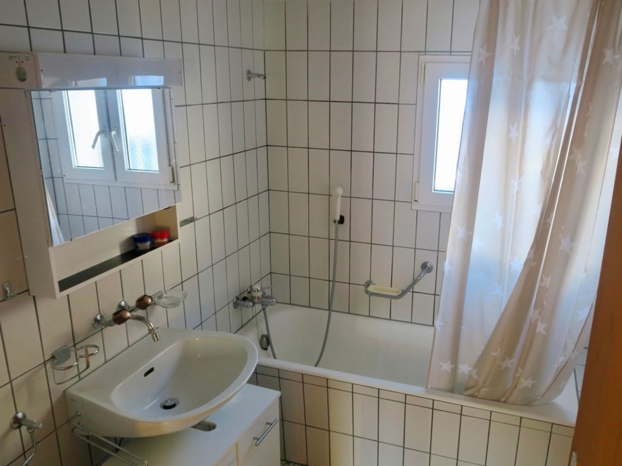 A bathroom with a bathtub, a sink, a mirror, and a window.