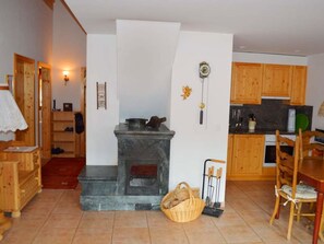 A cozy kitchen with wooden cabinets, a stone fireplace, and a dining area with a wooden table and chairs. - Tgèsa Bostgé Grubenmann, (Sedrun), 154.01 by Interhome (Sedrun)