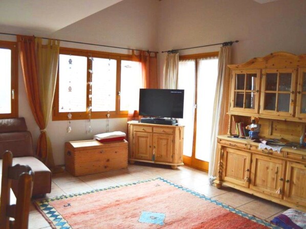 A living room with a television on a wooden cabinet, a sofa, a wooden cabinet with drawers, and a window with curtains. - Tgèsa Bostgé Grubenmann, (Sedrun), 154.01 by Interhome (Sedrun)