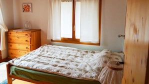 A bedroom with a wooden bed, a dresser, a window with curtains, and a wall-mounted picture. - Tgèsa Bostgé Grubenmann, (Sedrun), 154.01 by Interhome (Sedrun)