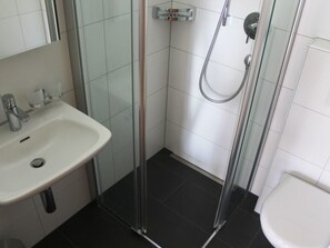 Ein Badezimmer mit Duschkabine, Waschbecken und Toilette.