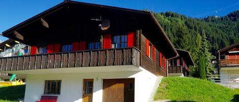 Un chalet doté d’un toit en pente, d’un balcon en bois et d’une porte en bois.