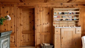 Un intérieur en bois avec une cheminée en pierre, des étagères en bois remplies de livres et un panier de bois de chauffage.