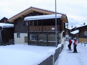 A wooden chalet with a balcony, surrounded by snow-covered ground. - Casa Zuela, (Segnas/Disentis), 1033 by Interhome (Disentis)