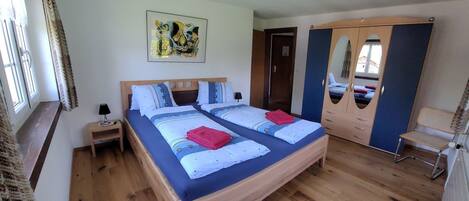A bedroom with a bed, a nightstand, a mirror, and a wardrobe.