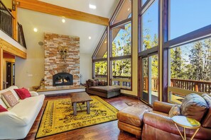 A spacious living room with a fireplace, large windows, and a balcony.