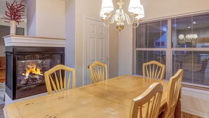 A dining room with a fireplace, wooden chairs, a chandelier, and a window with blinds. - Blk to Shuttle|BBQ|Near Gondola, Breck Rec Cntr (Breckenridge)