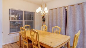 A dining area with a wooden table and chairs, a chandelier, and a window with blinds. - Blk to Shuttle|BBQ|Near Gondola, Breck Rec Cntr (Breckenridge)