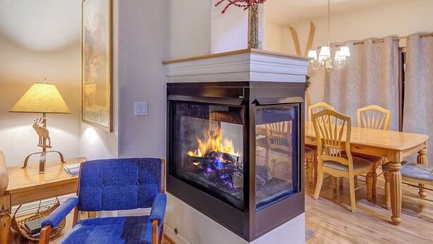 A living room with a fireplace, a dining table, chairs, a lamp, and a blue chair. - Blk to Shuttle|BBQ|Near Gondola, Breck Rec Cntr (Breckenridge)