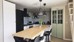 Una cucina moderna con isola centrale, sedie nere e una porta verde.