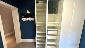 A walk-in closet with multiple shelves and hanging space, a coat rack, and a small shelf with decorative items. - Full Yorkville House 3Bed w/ Spa, Gym, Parking (Toronto)
