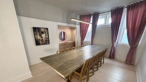 A dining area with a long wooden table, chairs, a mirror, and a painting on the wall. - Full Yorkville House 3Bed w/ Spa, Gym, Parking (Toronto)
