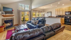 Ein geräumiger Wohnbereich mit Kamin, Ledersofa und einer Küche im Hintergrund.