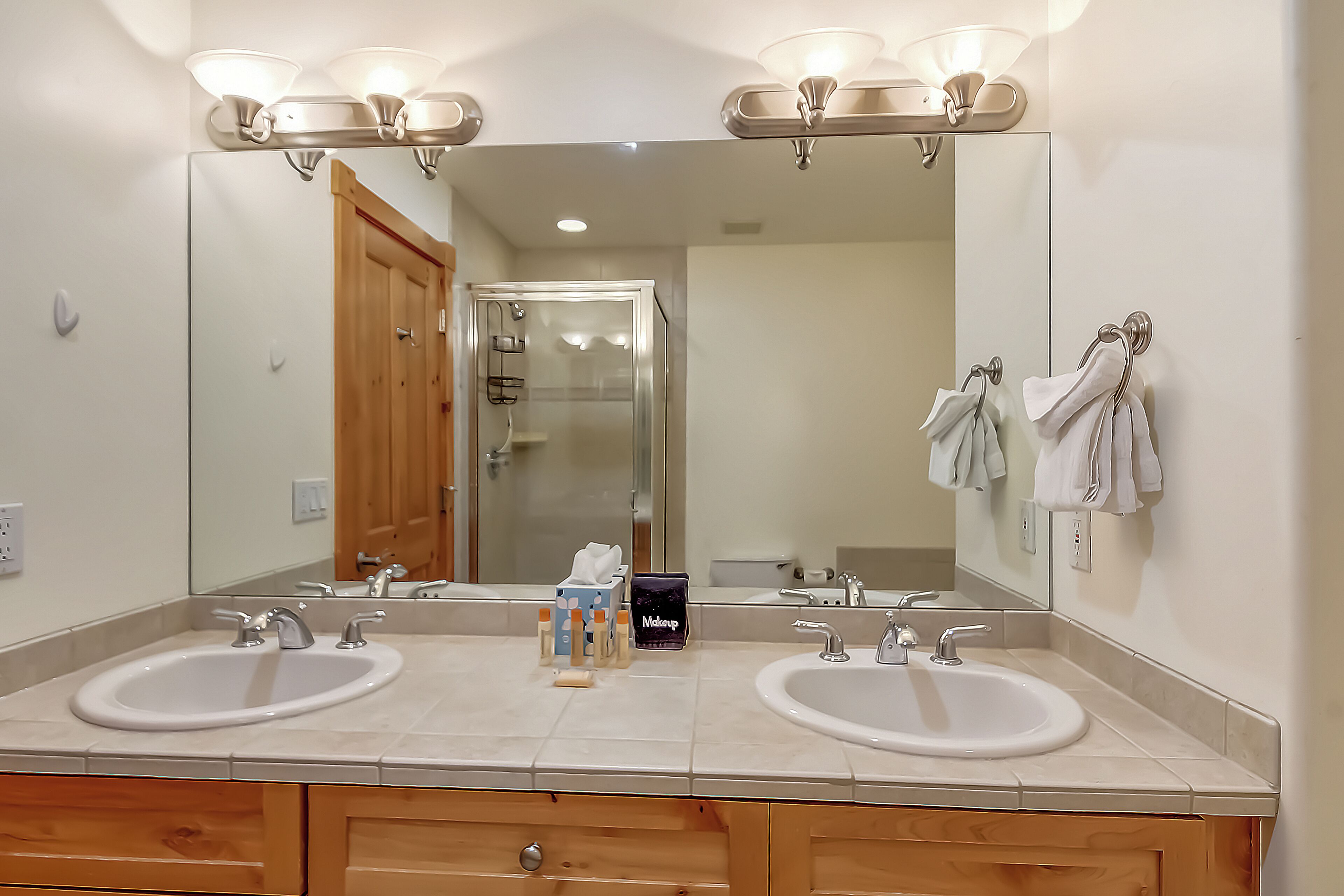 A bathroom with two sinks, a large mirror, and a wooden vanity.