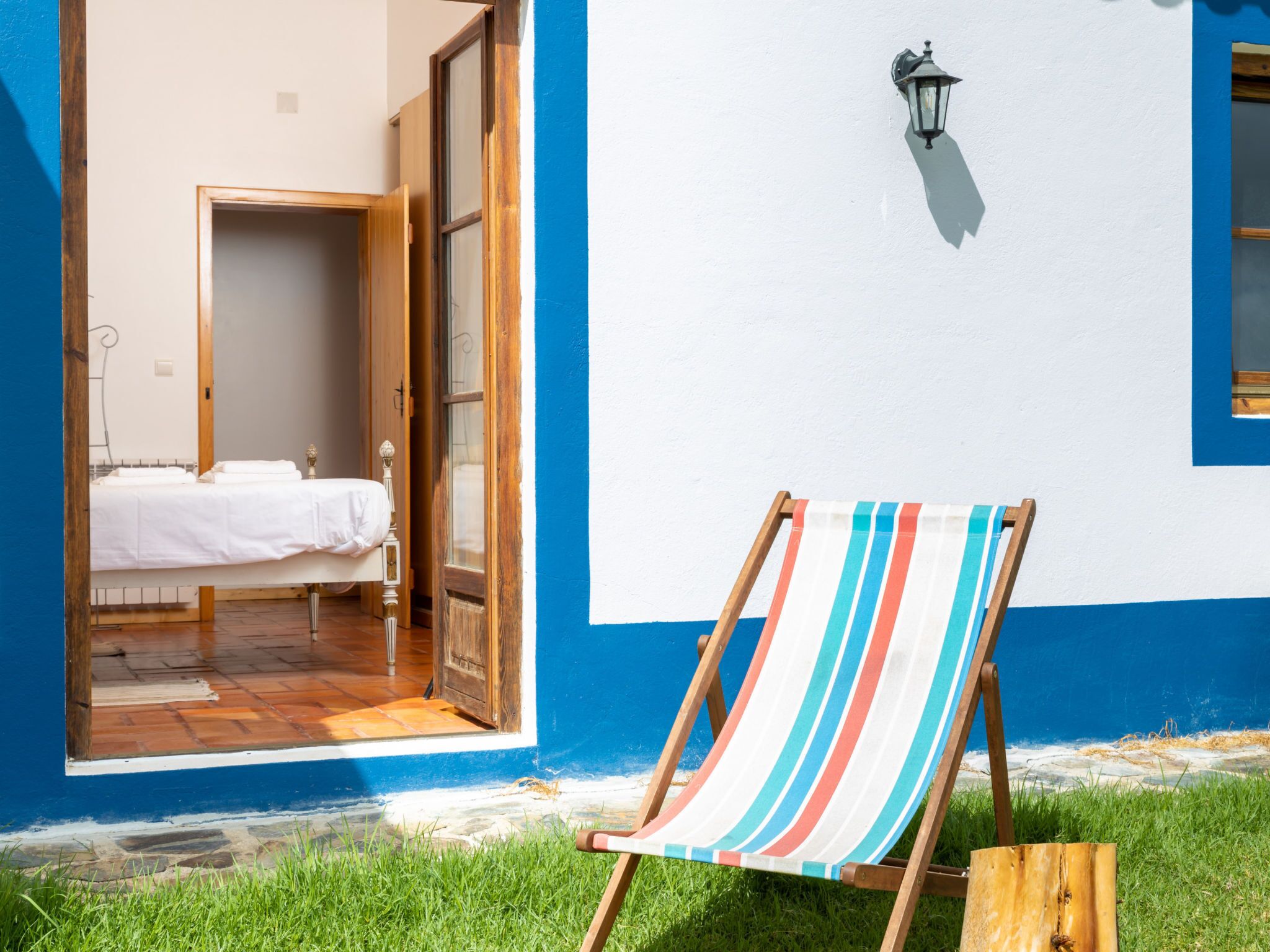 Une chambre avec un lit, une porte ouverte donnant sur une autre pièce et une vue sur la plage.