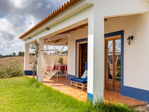 A house with a covered patio, a hammock, and a blue outdoor chair. - MONTE CERRO DA VIGIA by Interhome (São Luís)