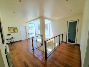 A spacious room with wooden flooring, a glass railing, and a door leading outside. - VILLA FATI by Interhome (Tróia)