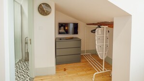 A hallway with a wooden floor, a grey storage unit, a wall-mounted TV, and a clothes drying rack. - Apartment  by Interhome (Porto)