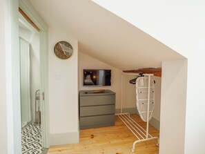 A hallway with a wooden floor, a grey storage unit, a wall-mounted TV, and a clothes drying rack. - Apartment  by Interhome (Porto)
